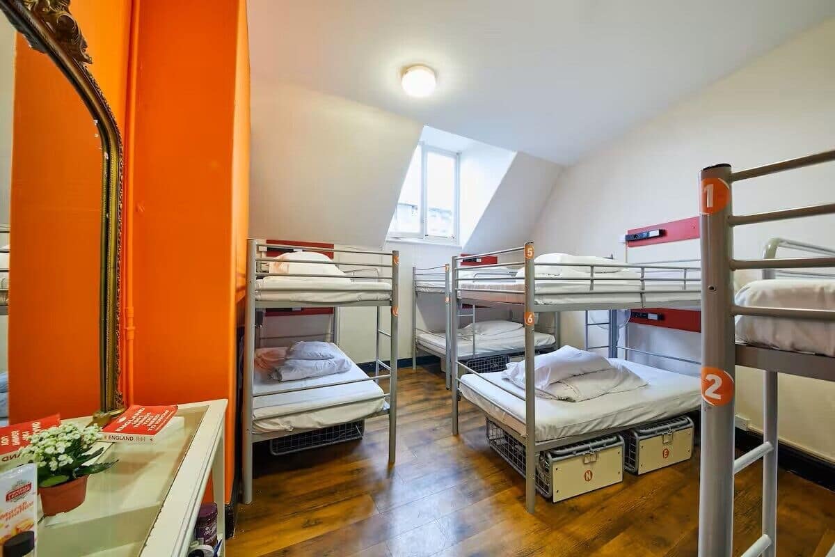 A dormitory room with bunk beds, a skylight, and a mirror on the left.