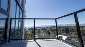 En balkon med frit udsyn over bybilledet, inklusive bygninger og et fjerntliggende bjerglandskab.