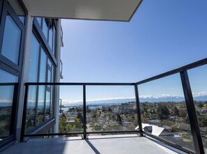 Ein Balkon mit freiem Blick auf eine Stadtlandschaft, inklusive Gebäude und einer fernen Bergkette.