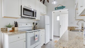A kitchen with white cabinets, a microwave, a stove, and a refrigerator.