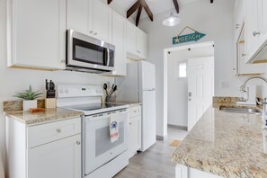A kitchen with white cabinets, a microwave, a stove, and a refrigerator.