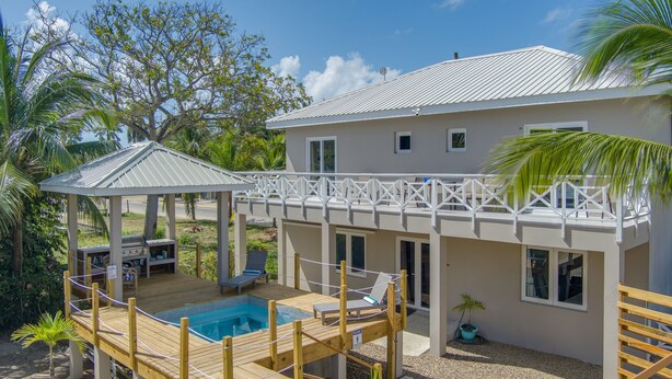A two-story house with a pool, deck, and a covered patio area.