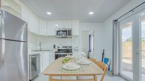 A modern kitchen with white cabinetry, stainless steel appliances, and a dining area with a wooden table and chairs.