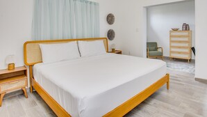 A bedroom with a wooden bed, a nightstand, a lamp, a chair, a dresser, and a wall-mounted air conditioner.