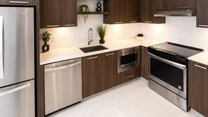Een moderne keuken met roestvrijstalen apparatuur, houten kastjes en een wit aanrecht.