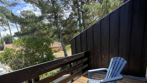 Una terraza de madera con dos sillas Adirondack y una valla de madera.