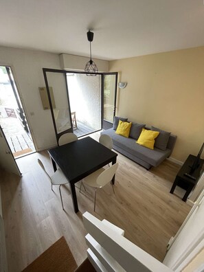 A modern living space with a dining area, a sofa with cushions, a ceiling fan, and a sliding glass door leading to an outdoor area.