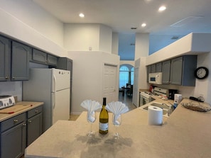 A modern kitchen with grey cabinets, a refrigerator, a microwave, and a sink. - 296 -Relaxing 4-Bedroom Villa with Private Pool, Spa & Games Room (Clermont)