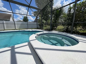 A swimming pool with a hot tub, surrounded by a covered area with a view of trees and a white fence. - 296 -Relaxing 4-Bedroom Villa with Private Pool, Spa & Games Room (Clermont)