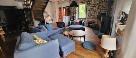Una sala de estar con un sofá azul, una mesa de centro redonda y una pared de piedra.
