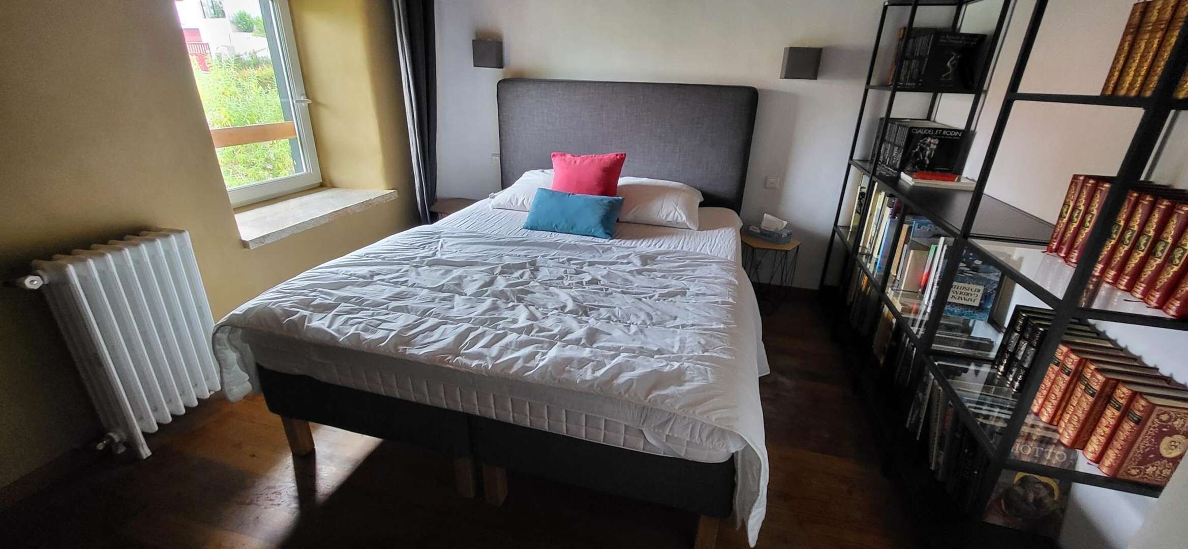 A bedroom with a bed, bedside table, and a bookshelf.