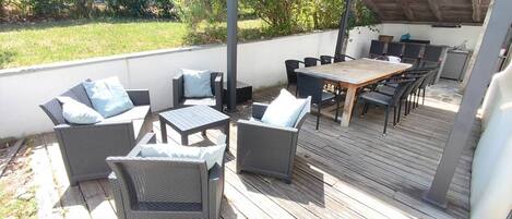An outdoor patio with wicker furniture, a wooden table, and a covered seating area.