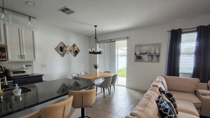 Eine moderne Küche mit Kochinsel, Essbereich mit Stühlen, einer Couch und einem Gemälde an der Wand.