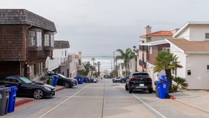 Una calle costera con automóviles estacionados, edificios y vistas al océano.