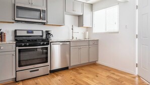 Una cocina equipada con microondas, estufa, horno y lavavajillas.