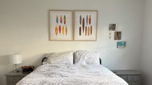 Un dormitorio con cama, ventilador de techo, mesita de noche con lámpara y decoración en la pared.