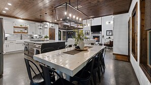Una cucina moderna con una grande isola, soffitto in legno e illuminazione a sospensione.