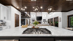 Una cucina moderna con isola centrale, elettrodomestici in acciaio inossidabile e soffitto in legno scuro.