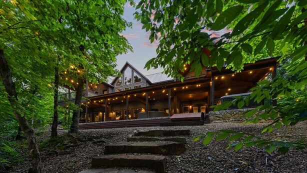 Un lodge in legno con un portico coperto, gradini in pietra e luci a stringa.