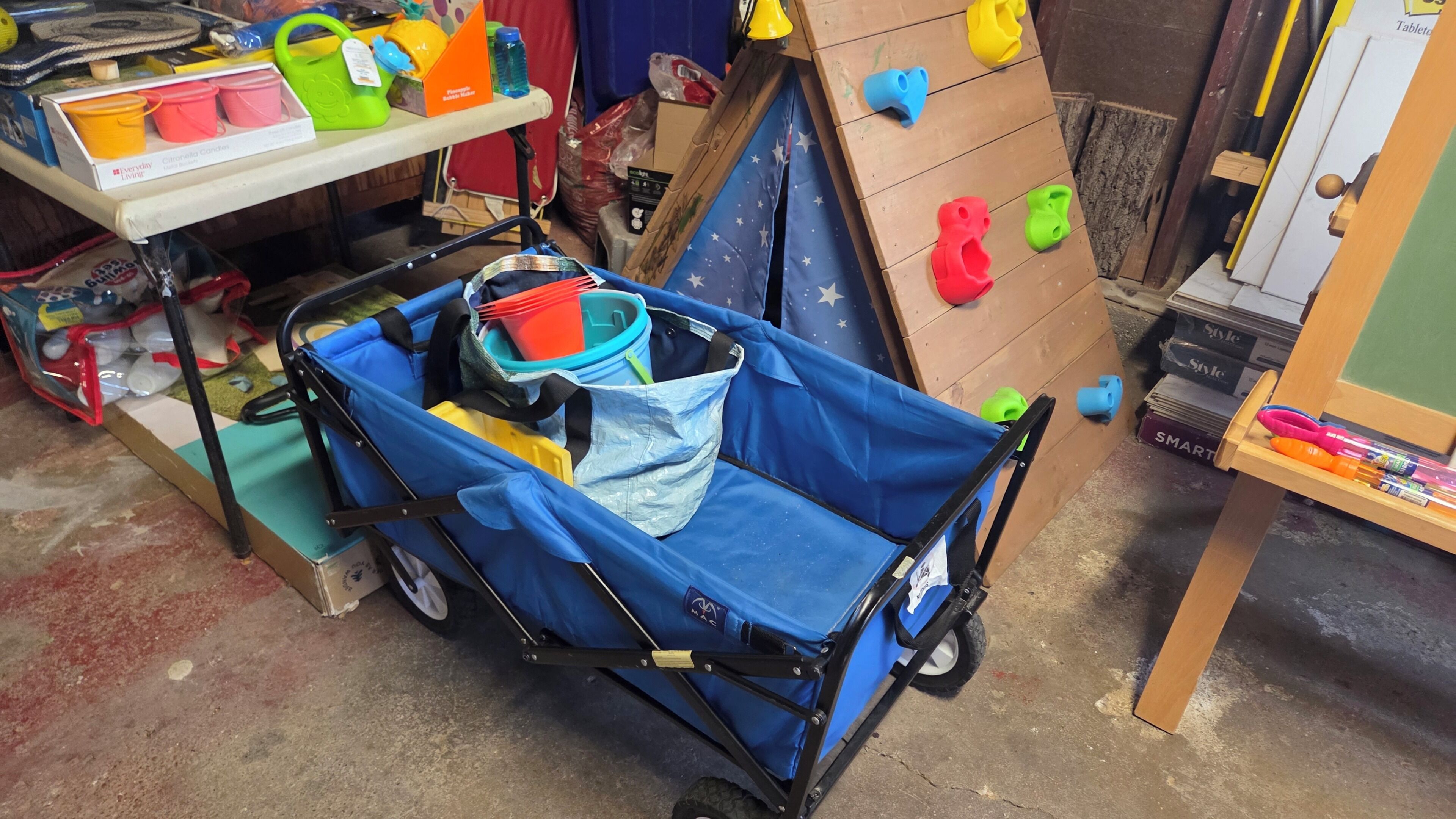Un chariot de rangement avec une housse bleue, un sac en plastique et un récipient jaune.