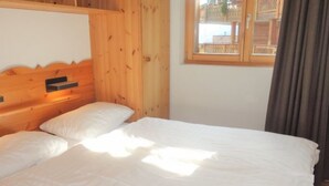 Una stanza in legno con un letto, una finestra vista e una tenda.