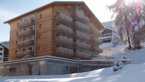 Un edificio in legno a più piani con balconi, immerso in un paesaggio innevato.