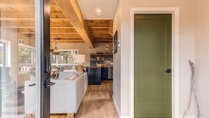 Un interno moderno con soffitto in legno, una cucina con schienale a contrasto bianco e nero e una porta verde.