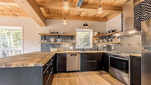 Una cucina moderna con travi in legno a soffitto, elettrodomestici integrati e una schiena di top in motivo a spina di pesce.