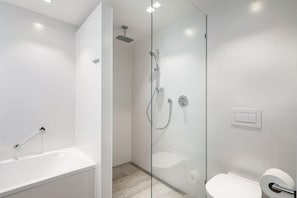 Ein modernes Badezimmer mit einer Glasdusche, einer freistehenden Badewanne und einem WC.