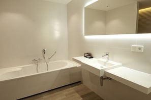 Ein modernes Badezimmer mit freistehender Badewanne, einem Waschtisch mit Spiegel und einer Duschbrause.