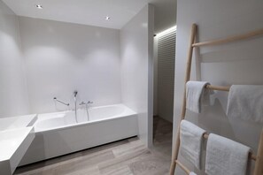 A modern bathroom with a freestanding bathtub, a wooden towel rack, and a white sink. - Van Der Valk Vianen (Vianen)