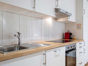 A modern kitchen with white cabinets, stainless steel appliances, and a wooden countertop. - Apartment  by Interhome (Lucerne)