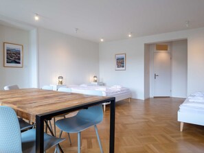 A modern hotel room with a wooden dining table, two beds, and a large window. - Apartment  by Interhome (Lucerne)
