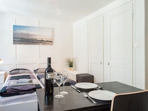 A neatly arranged room with a bed, a dining table set for two, a bottle of wine, and a small potted plant. - Apartment  by Interhome (Zurich)