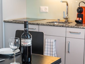 A bottle of wine and a glass on a table in a modern kitchen with a granite countertop, a coffee machine, and a towel hanging on the wall. - Apartment  by Interhome (Zurich)