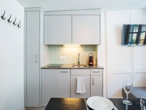 A compact kitchen with a countertop, sink, and a television mounted on the wall. - Apartment  by Interhome (Zurich)