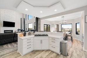 A modern kitchen with a large island, built-in appliances, and a view to the outside.