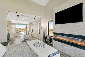 A modern hotel room with a fireplace, a large TV, and a view of the outdoors.