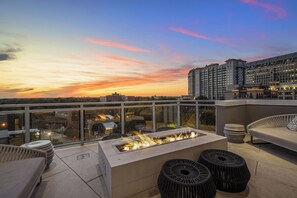 A rooftop terrace with a fire feature, outdoor seating, and a city view at sunset. - Buckhead Sky Retreat (Atlanta)