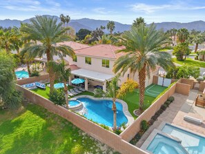 Una propiedad residencial con piscina, palmeras y vistas a las montañas.