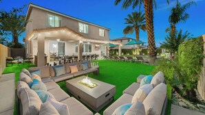 Una casa moderna con un patio, mobiliario exterior y un hogar.