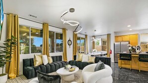 Una sala de estar moderna con sofá, sillones, una mesa de centro y una zona de cocina con refrigerador.