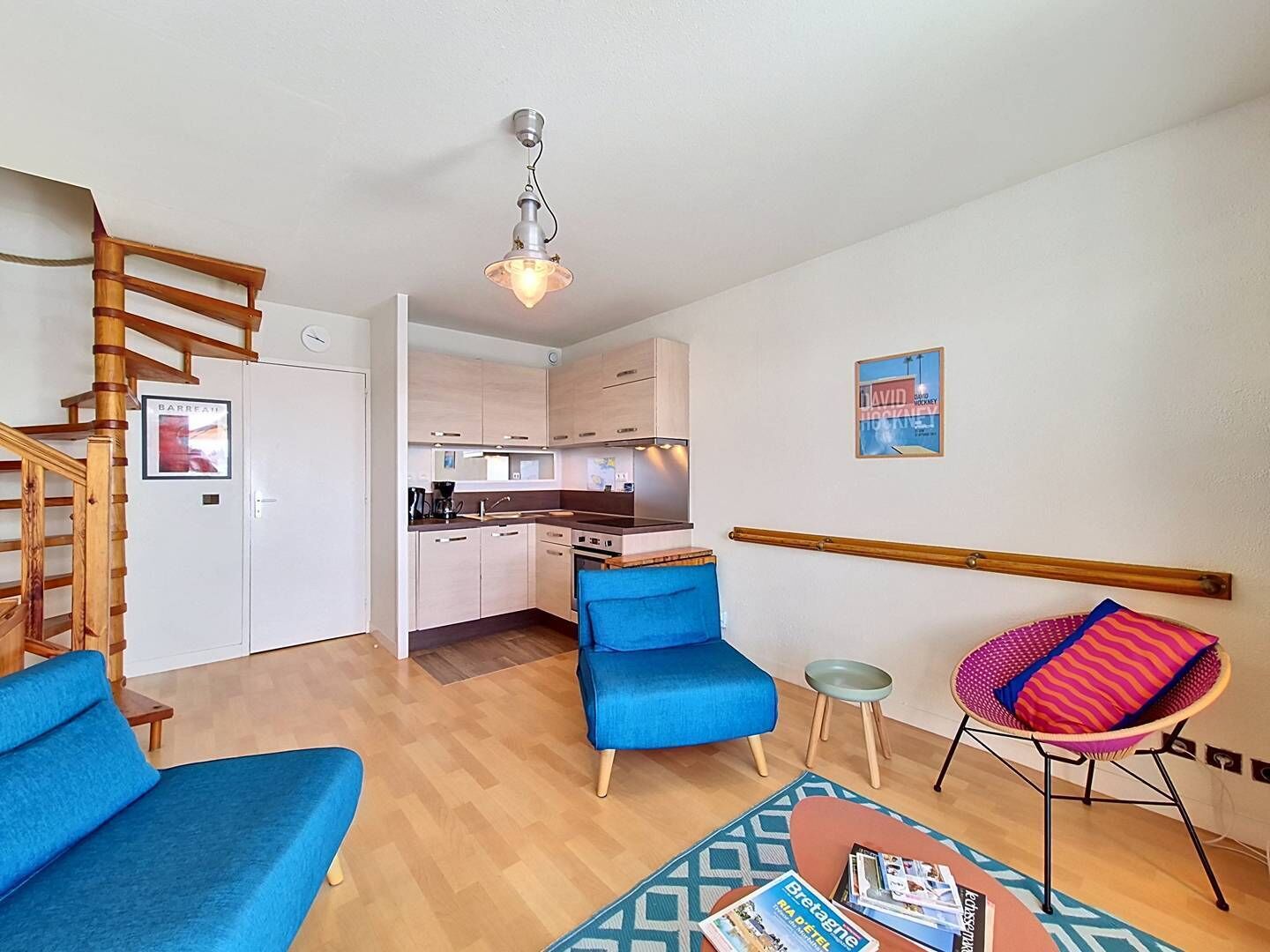 A compact living space with a kitchenette, a blue sofa, a small dining table, and a chair.