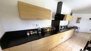 Een moderne keuken met een zwart aanrecht, houten kastjes en een zwarte afzuigkap.