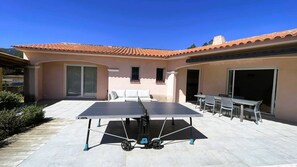 An outdoor patio with a ping pong table, a seating area with a sofa and chairs, and a building with a tiled roof. - Villa Luna, 8 pers, piscine, 10 mn plage en voiture (LECCI)