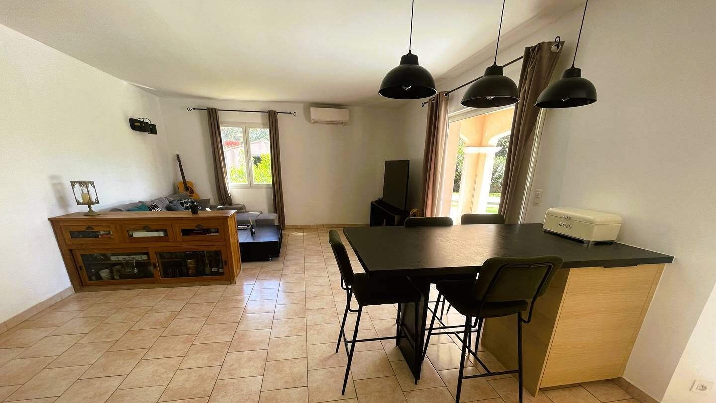 Un espace de vie compact comprenant un coin repas, une kitchenette et une vue sur l’extérieur.