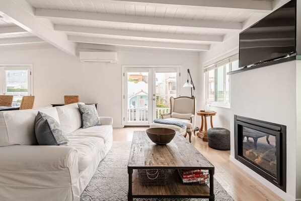 A modern living room with a sofa, coffee table, fireplace, and a view of the outside.