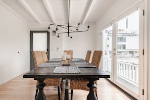 A dining area with a table, chairs, a chandelier, and a view through a large window.
