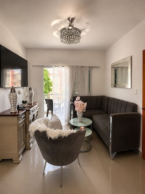 A modern living room with a sofa, armchair, and a small table with flowers. - Modern, comfortable and safe in SFM with free parking and a (San Francisco de Macorís)