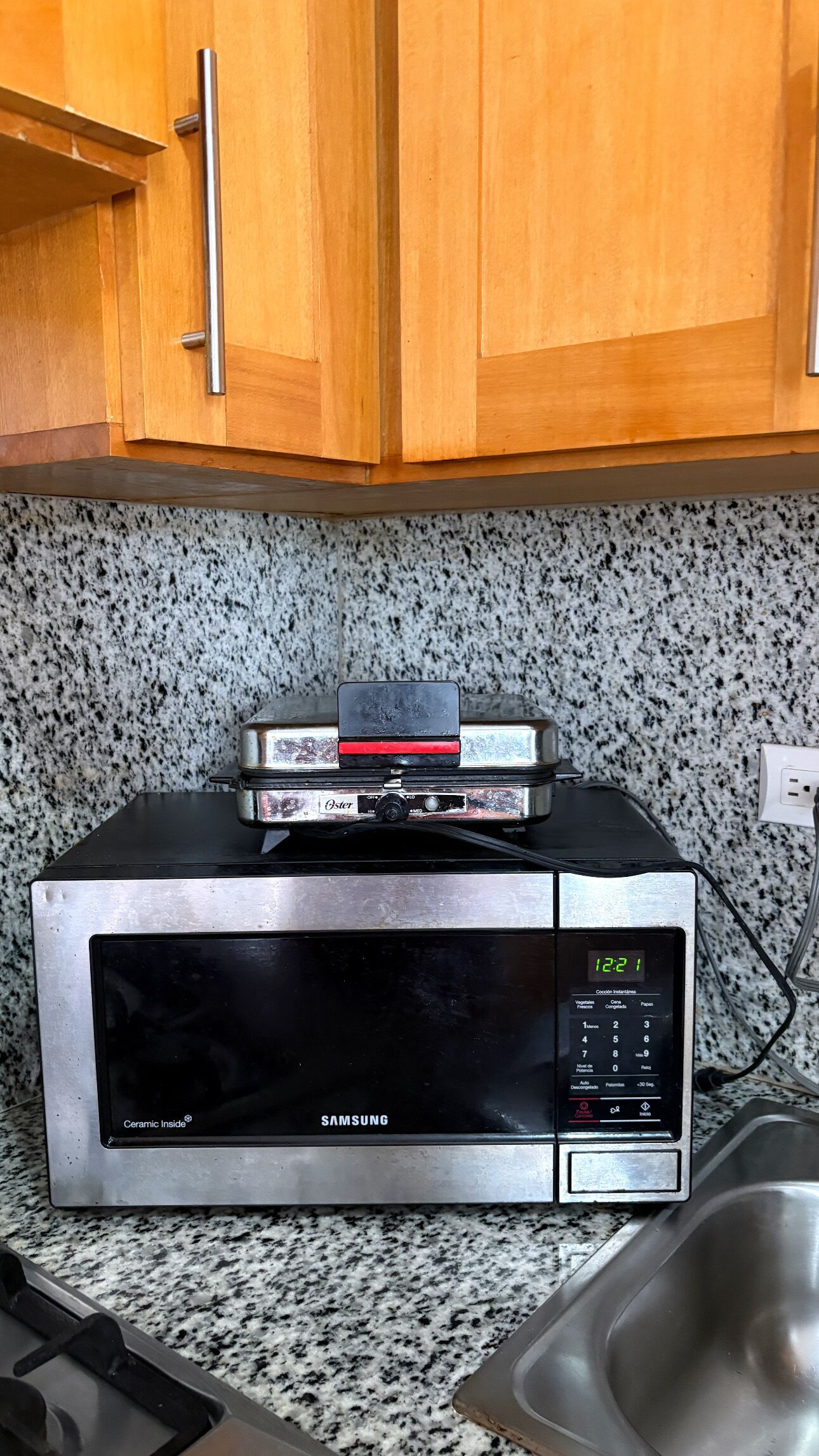 Een keuken met een magnetron, een broodrooster en houten kastjes.